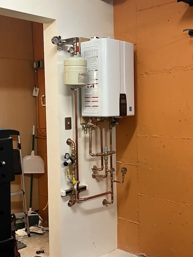 Plumbing technician inspecting water heater connections in Derby